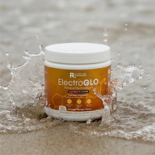 A white tub of ElectroGLO Orange Mango electrolyte powder sitting in splashing water on a sandy beach.