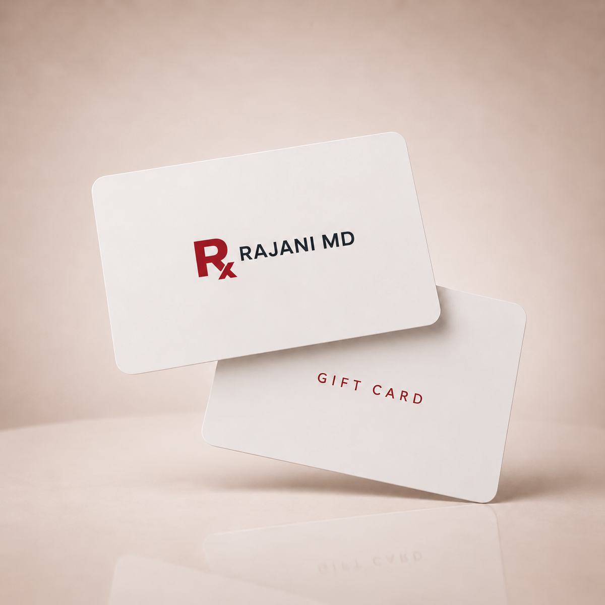 Two Rajani MD gift cards floating on a warm beige reflective surface. 