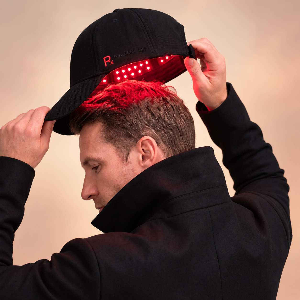 Man positioning the Rajani MD PlasmaGLO™ Hair+ Cap over his scalp for red LED and laser hair therapy.