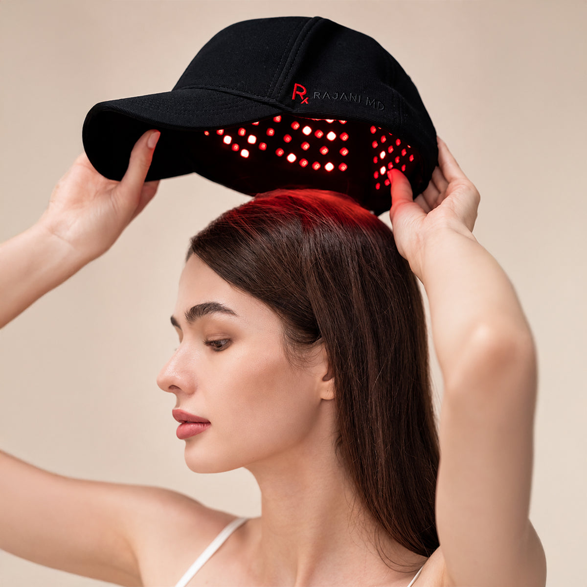 Woman wearing the Rajani MD PlasmaGLO™ Hair+ Cap, a cordless device for at-home scalp light therapy.