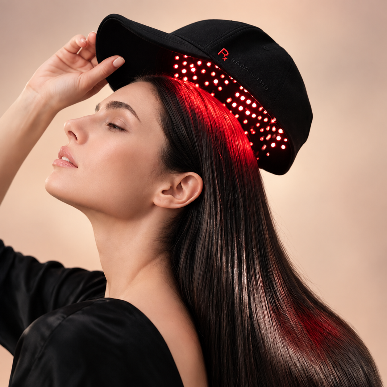 Woman positioning the Rajani MD PlasmaGLO™ Hair+ Cap over her head for at-home scalp light therapy.