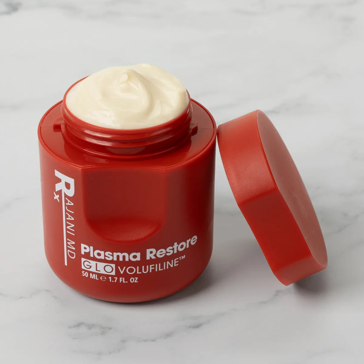 Open jar of Volufiline cream on white marble